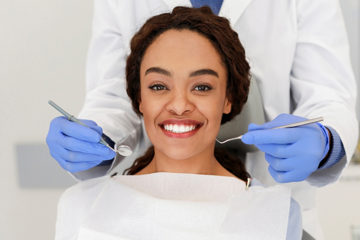 Smiling patient receiving dental care with tools during exam